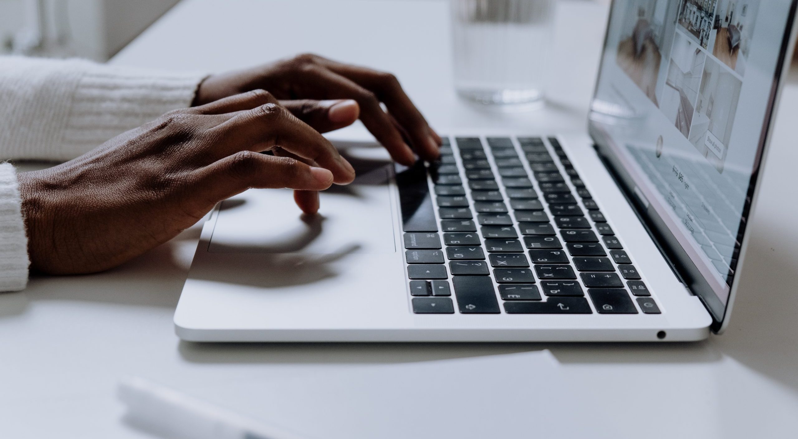 Person typing on a white laptop